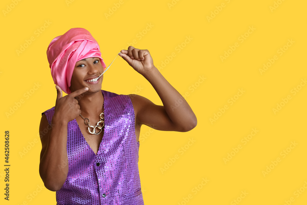 Glamorous African-American guy with chewing gum on color background