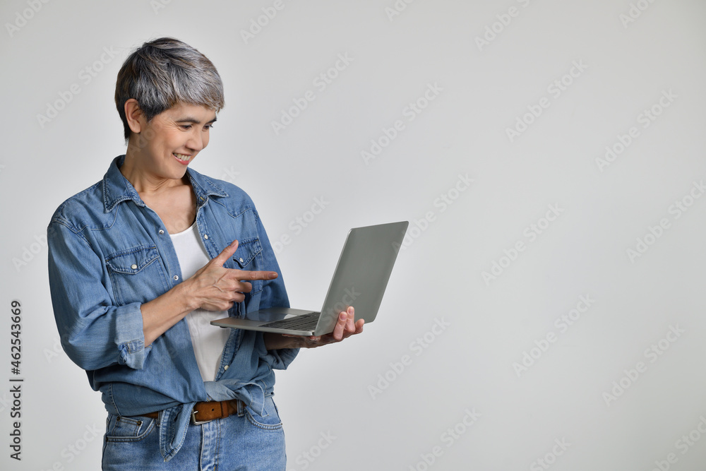 Portrait of middle aged Asian woman 50s wearing casual denim shirt white t-shirt holding laptop comp