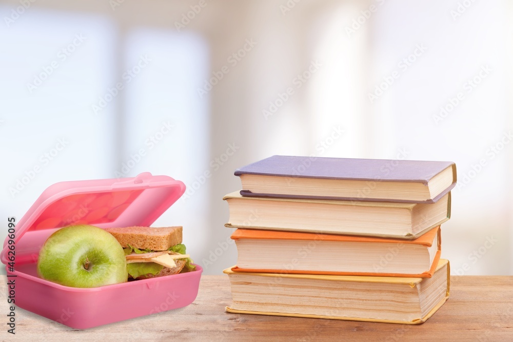 Healthy school lunch and school supplies on a wood background.