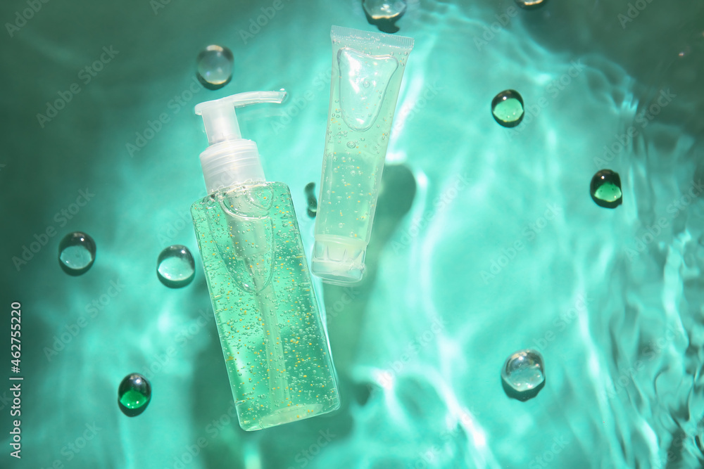 Cosmetic products in water on color background