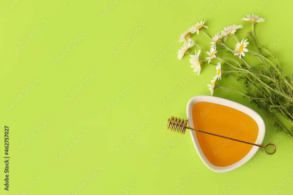 Bowl of sweet honey and chamomile flowers on color background