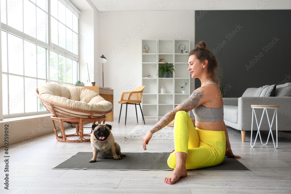 Young woman with cute pug dog practicing yoga at home