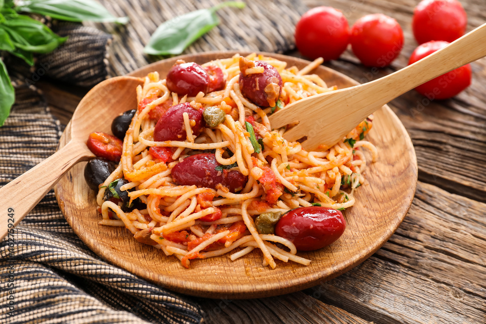 Plate of tasty Pasta Puttanesca on wooden background