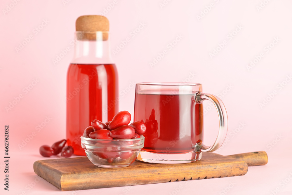 Cup and bottle of healthy dogwood berry drink on color background