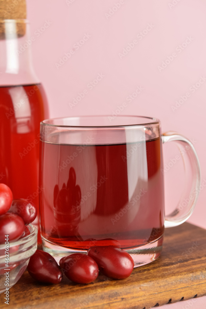 Cup of healthy dogwood berry drink on color background