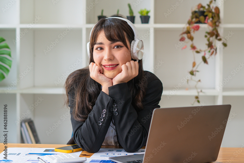 微笑的亚洲女商人戴着耳机使用笔记本电脑，快乐的女学生观看网络研讨会，列表