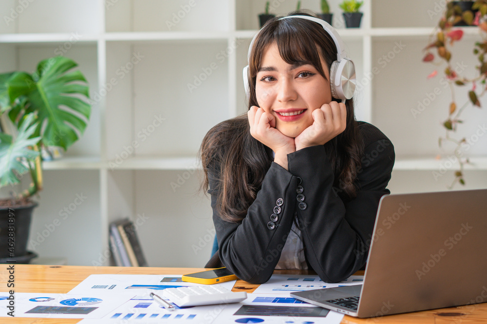 微笑的亚洲女商人戴着耳机使用笔记本电脑，快乐的女学生观看网络研讨会，列表