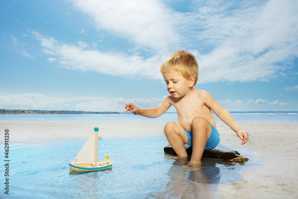 Playing with toy boat in the puddle on a sea beach