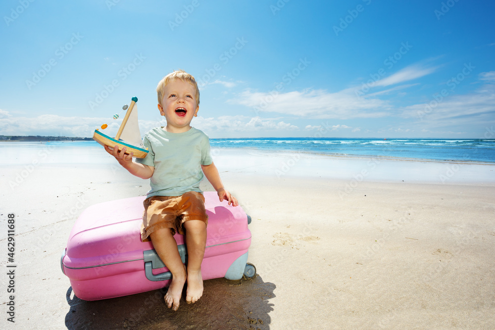 Boy play sail boat yacht sitting on a suitcase