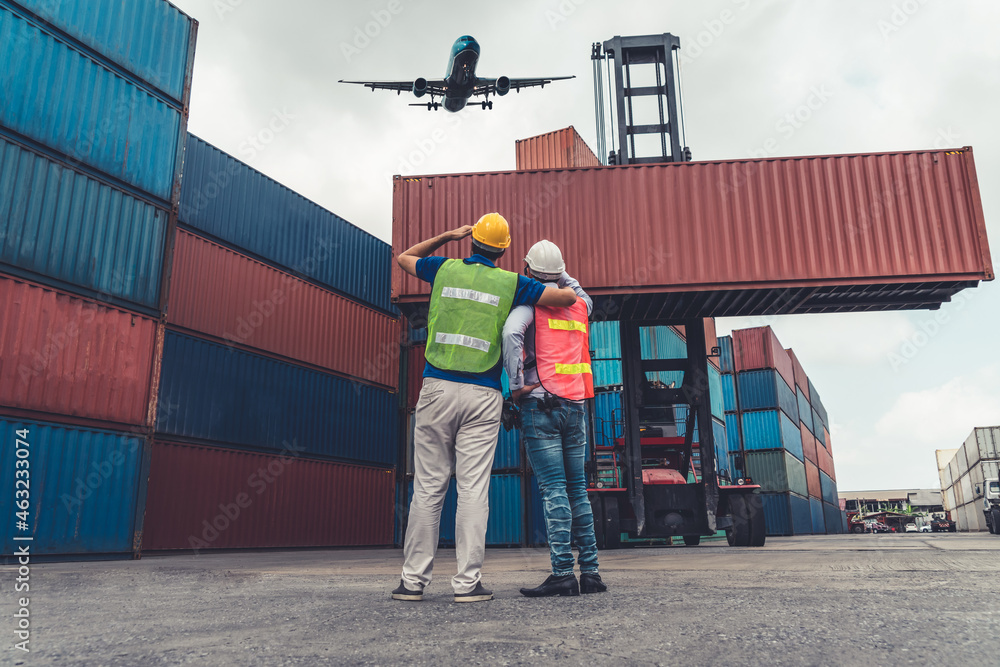 Industrial worker works with co-worker at overseas shipping container port . Logistics supply chain 