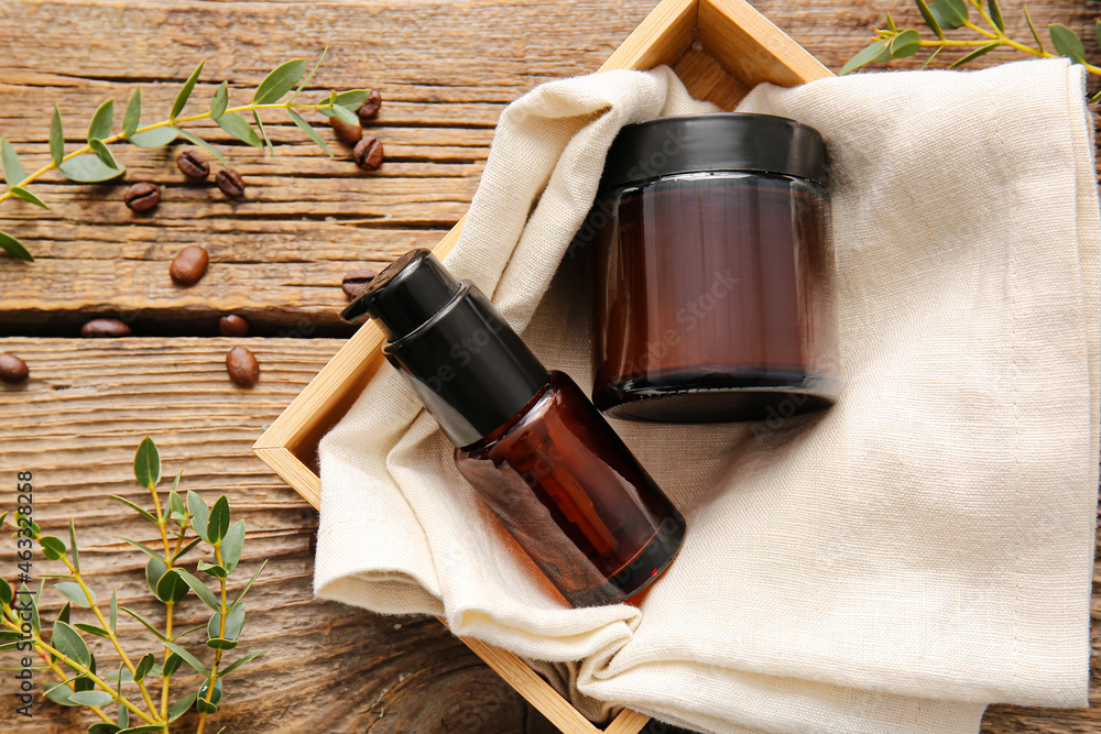 Composition with cosmetic products, plant branches and coffee beans on wooden background