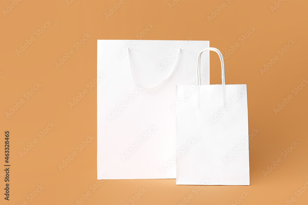 Blank paper bags on color background