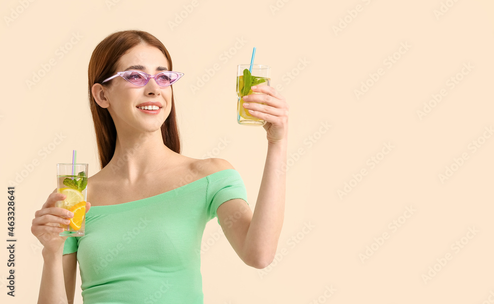 Beautiful young woman with fresh lemonade on light color background