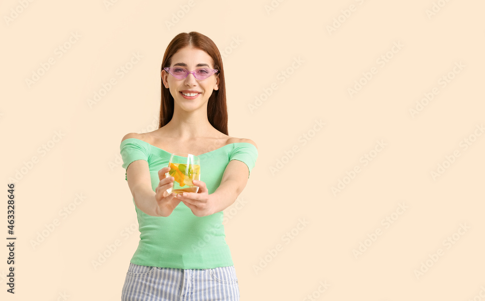 Beautiful young woman with fresh lemonade on light color background