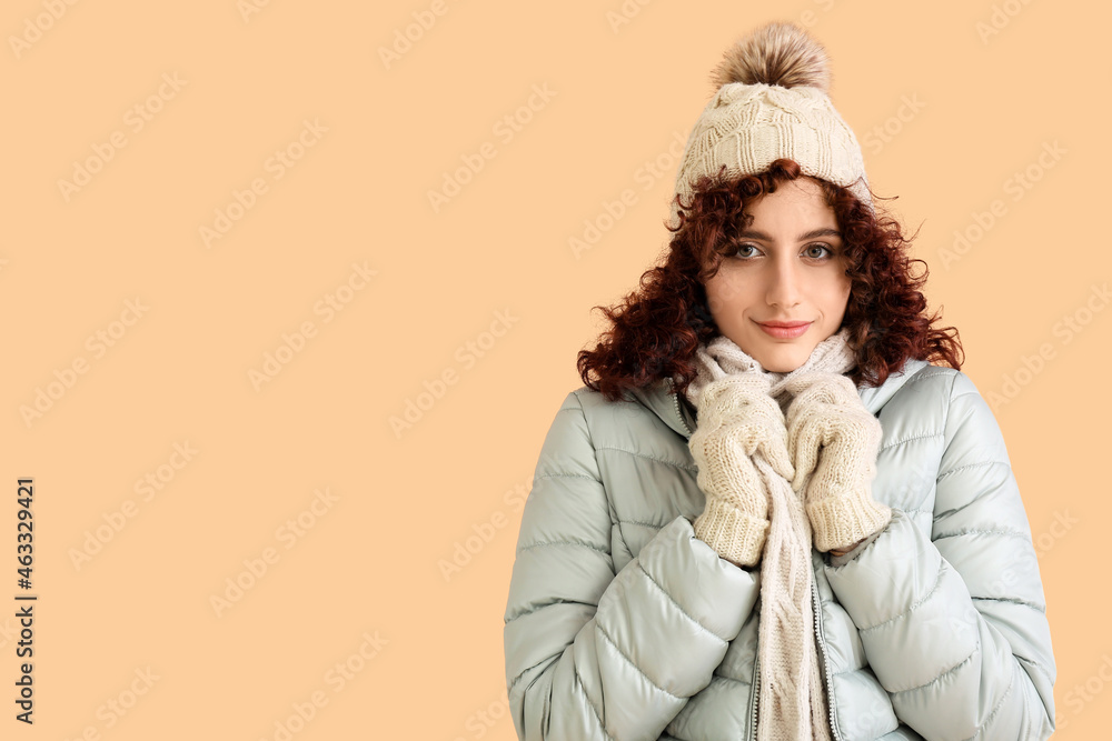 Frozen woman in winter clothes and knitted hat on color background