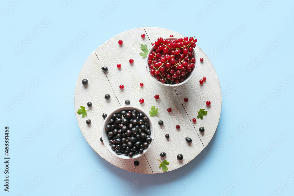 Bowls with ripe red and black currant on color background