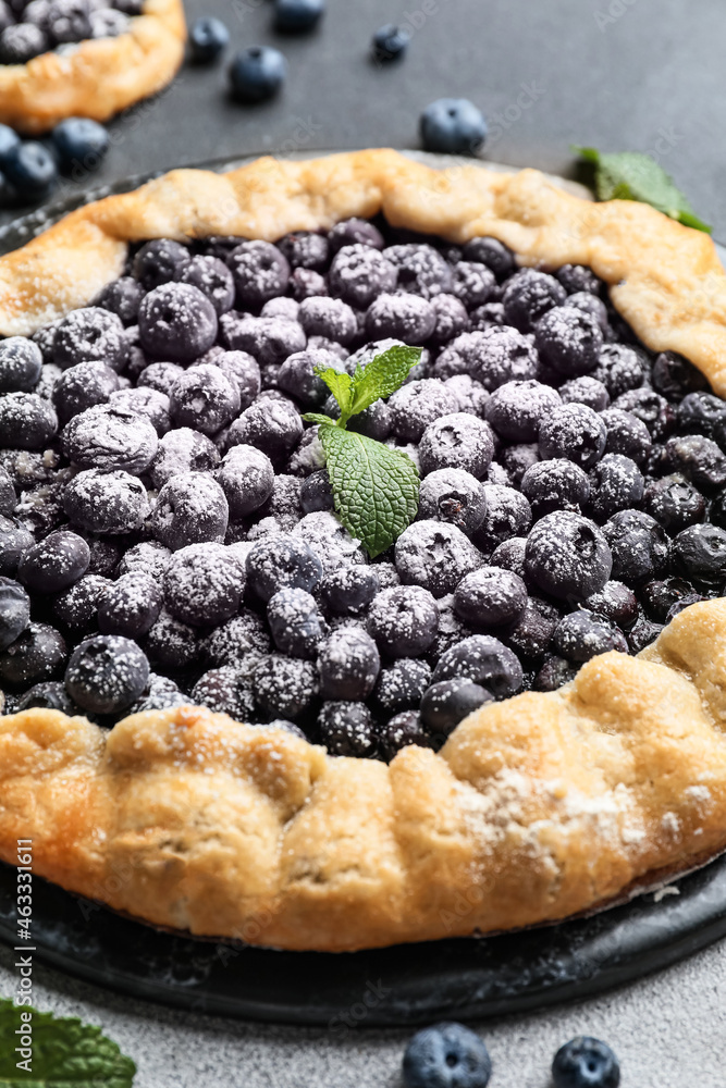 Plate with tasty blueberry galette on dark background, closeup