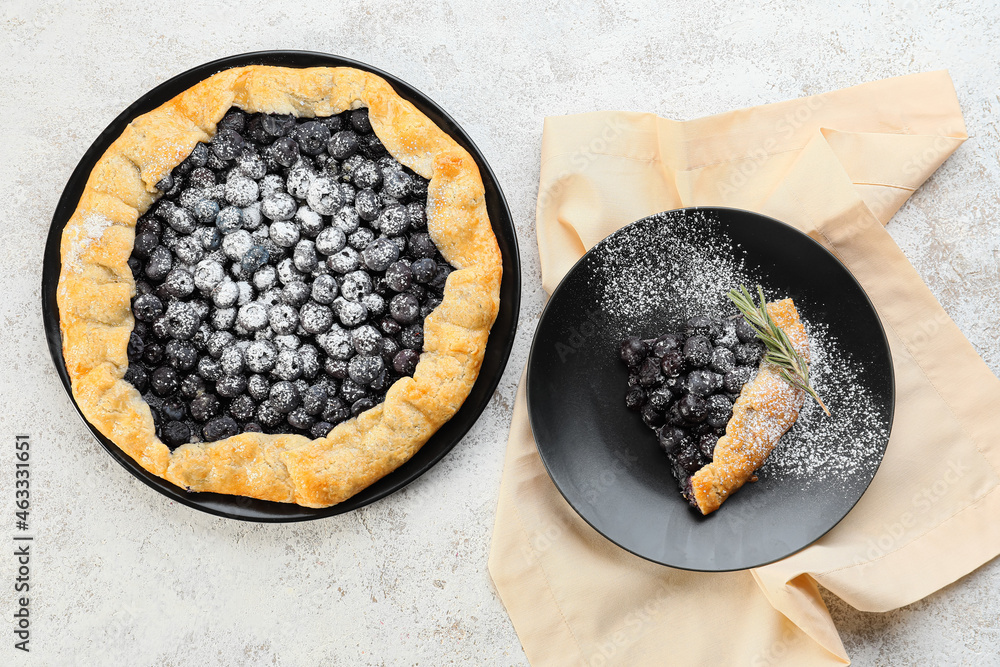 Plate with piece of tasty blueberry galette on light background