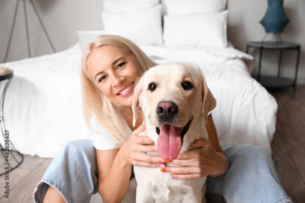 卧室里有一只可爱的拉布拉多犬的成熟女人