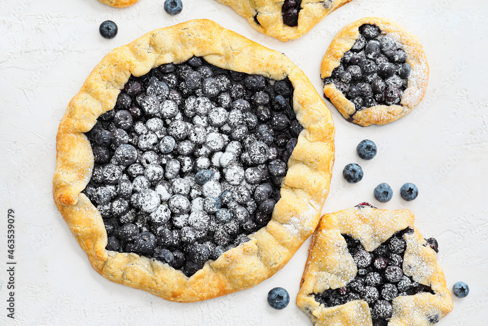 Tasty blueberry galettes on light background