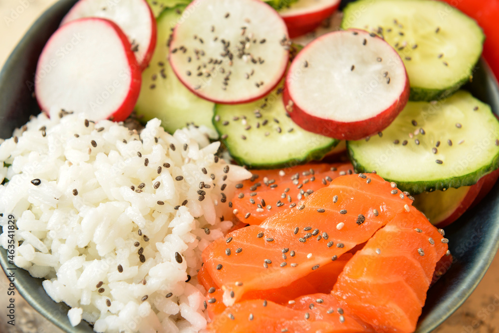 Tasty poke bowl with salmon and vegetables on table, closeup