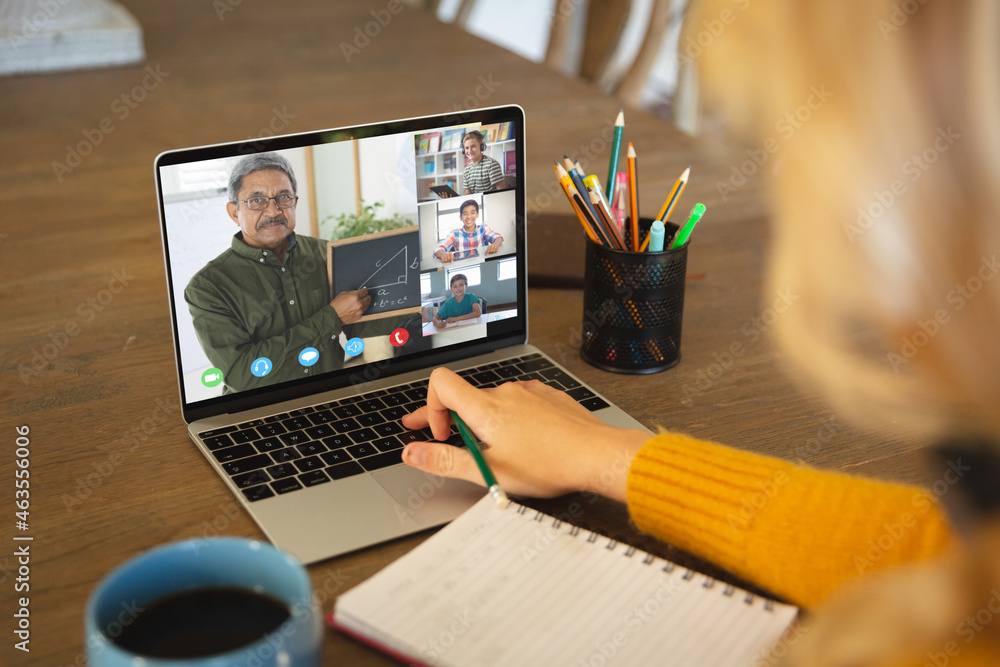 Caucasian woman using laptop for video call, with smiling diverse high school pupils on screen