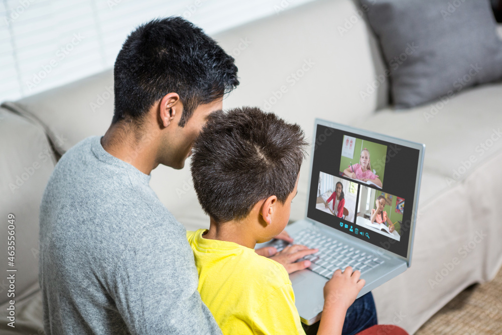 Biracial boy with father using laptop for video call, with elementary school pupils on screen