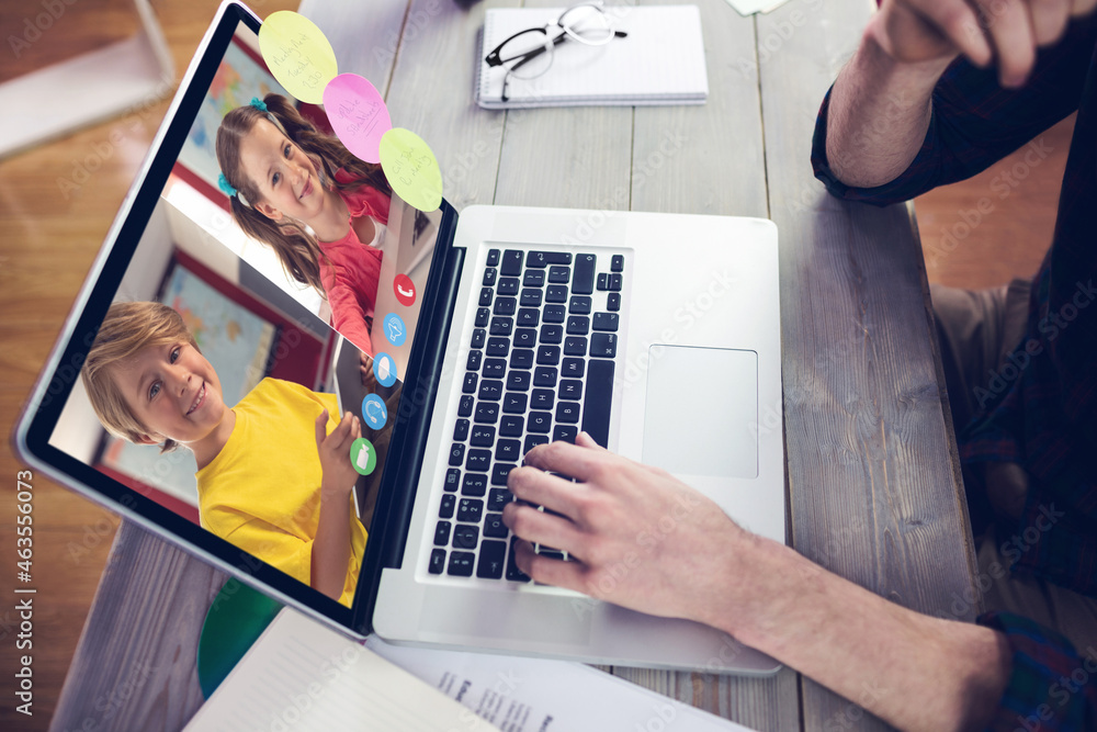 Hands of man using laptop for video call, with smiling caucasian elementary school pupils on screen