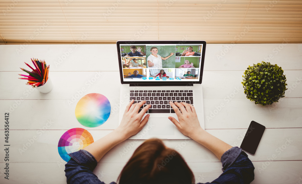 Caucasian woman using laptop for video call, with smiling diverse elementary school pupils on screen