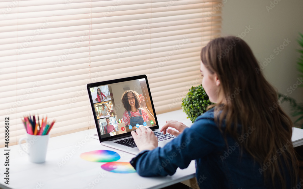 Caucasian girl using laptop for video call, with smiling diverse high school pupils on screen