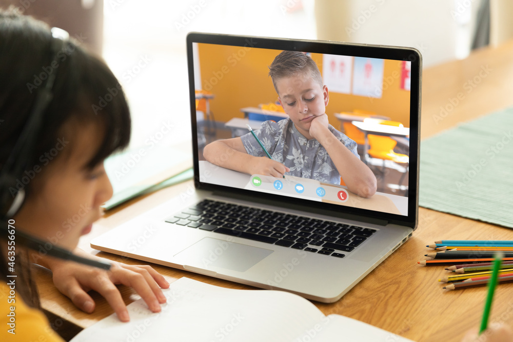 Asian girl using laptop for video call, with elementary school pupil on screen