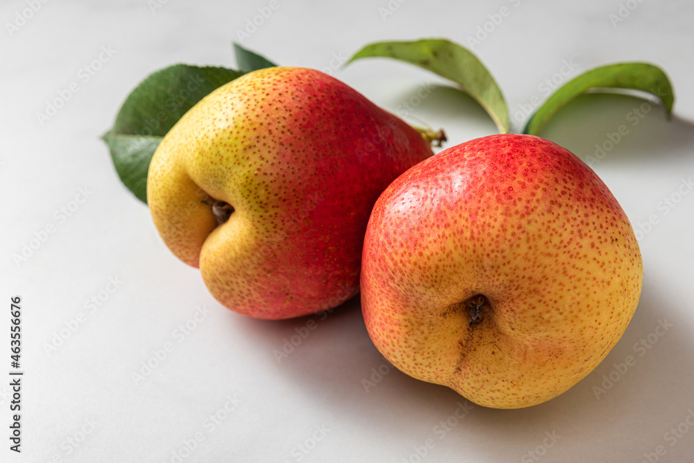 Fresh ripe pears with green leaves on white background. Close up