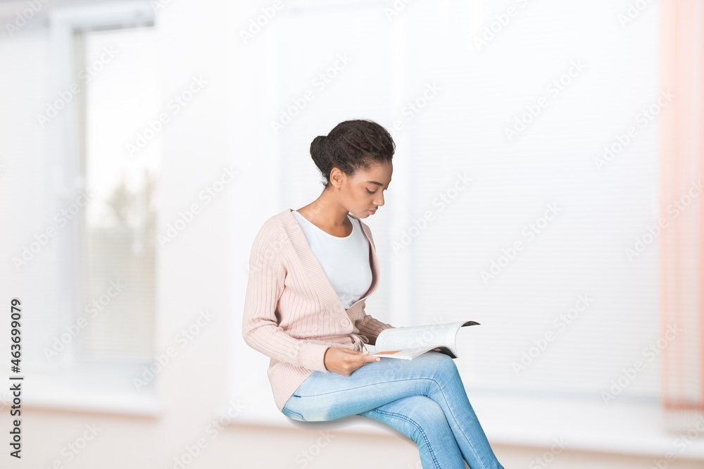 Free Time To Relax. Beautiful woman sitting on windowsill at home, reading a paper book,