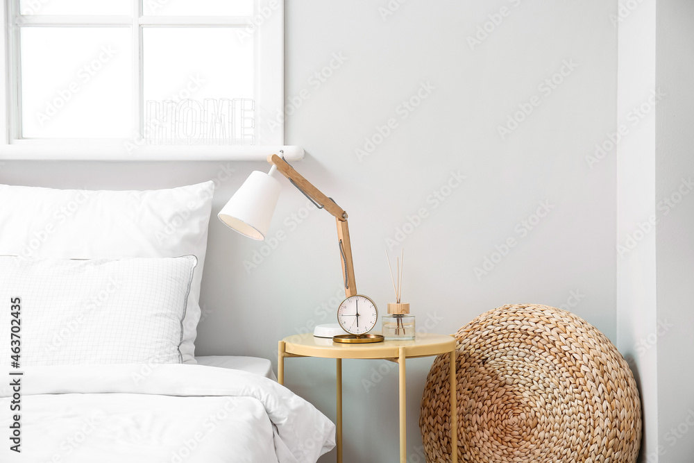 Alarm clock and stylish lamp on bedside table