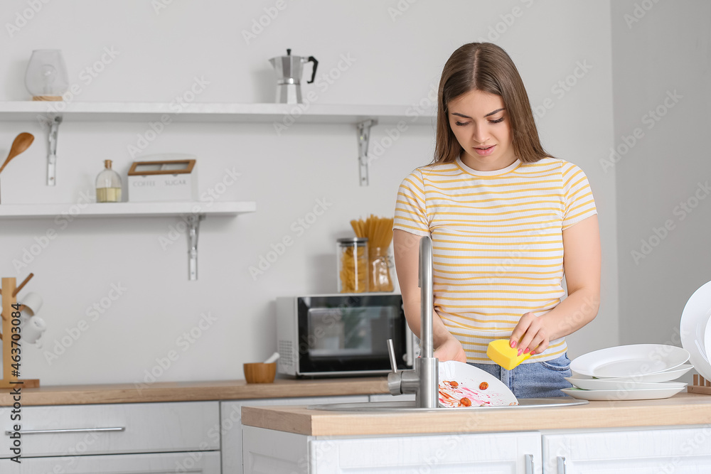 Young woman washing dish in kitchen