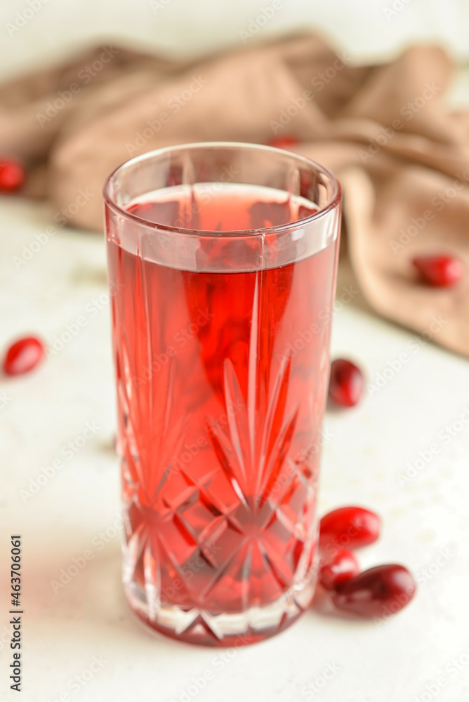 Glass of healthy dogwood berry drink on light background