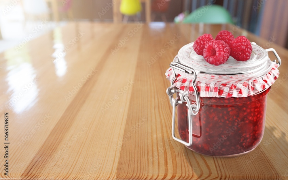 Tasty sweet berry jam on the retro decorated desk with fruit and glass jar.