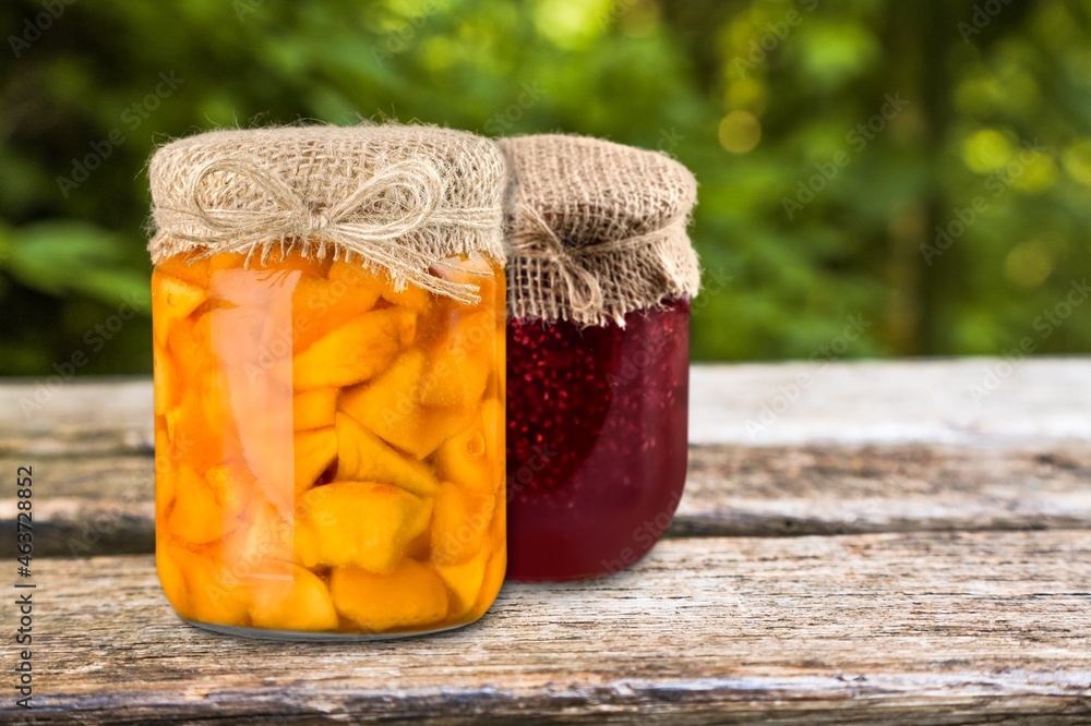 Tasty sweet berry jam on the retro decorated desk with fruit and glass jar.