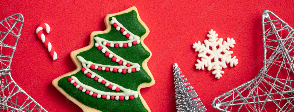 Decorated Christmas gingerbread cookies with decorations on red table background.