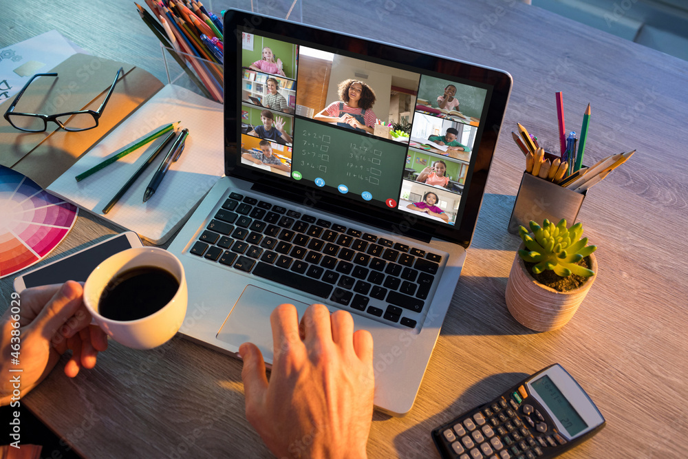 Hands of man using laptop for video call, with smiling diverse elementary school pupils on screen