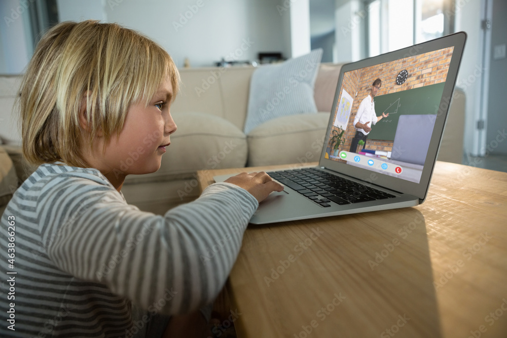 Caucasian boy using laptop for video call, with biracial male teacher on screen