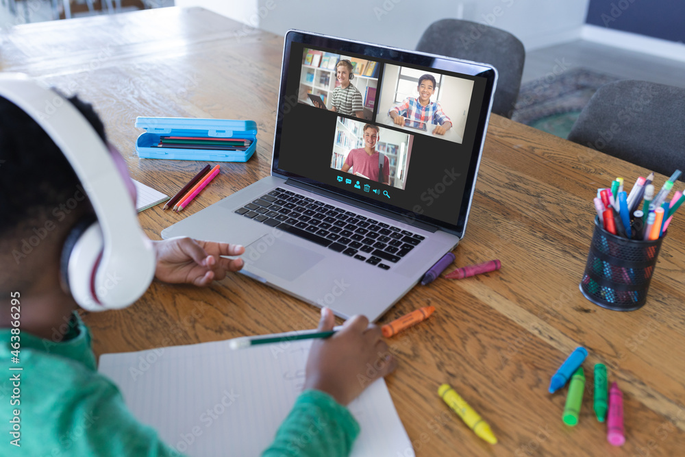 African american boy using laptop for video call, with diverse high school pupils on screen