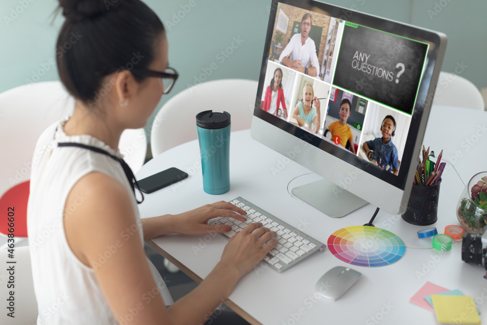 Caucasian girl using laptop for video call, with smiling diverse elementary school pupils on screen