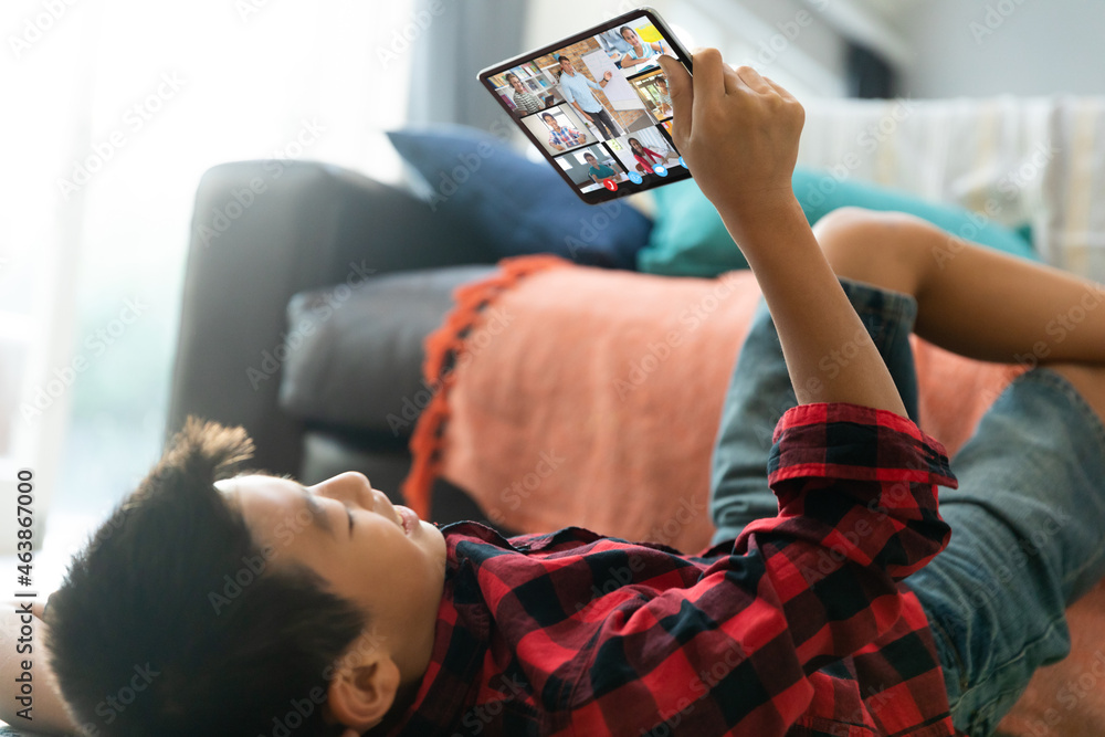 Smiling asian boy using tablet for video call, with smiling diverse high school pupils on screen