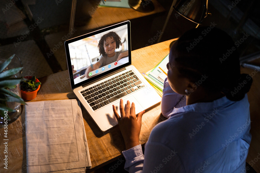 African american woman using laptop for video call, with smiling elementary school pupil on screen