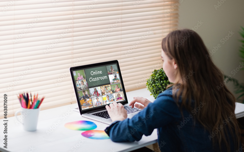 Caucasian woman using laptop for video call, with diverse elementary school pupils on screen