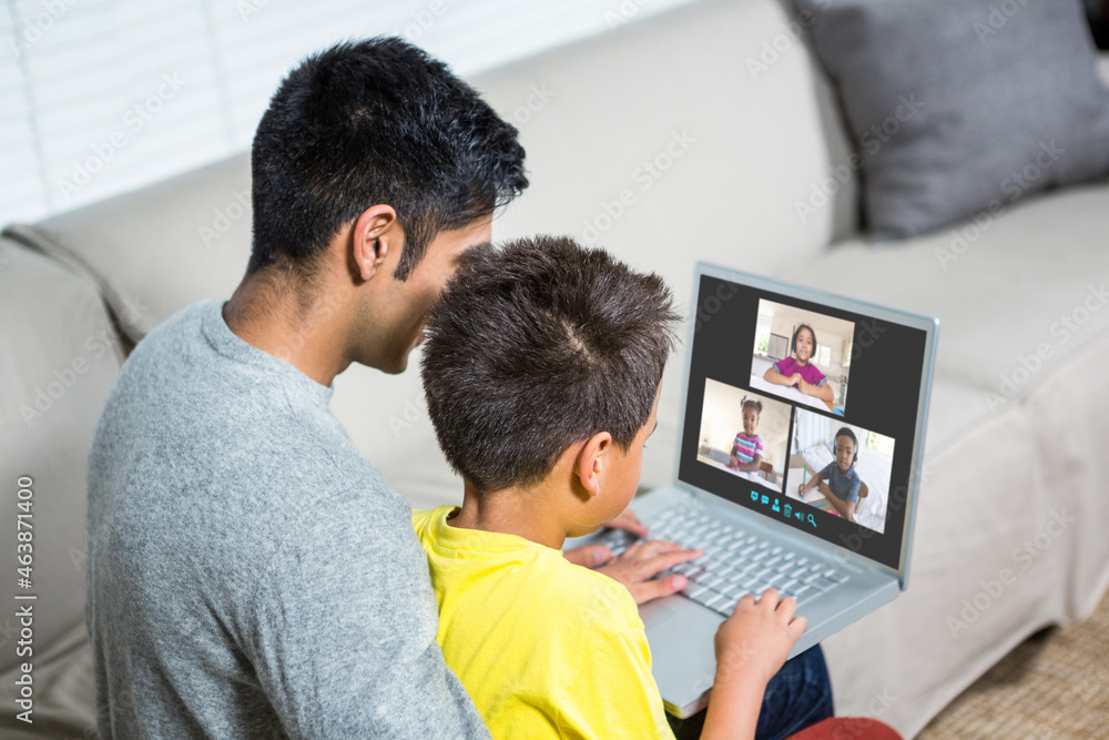 Biracial boy with father using laptop for video call, with elementary school pupils on screen