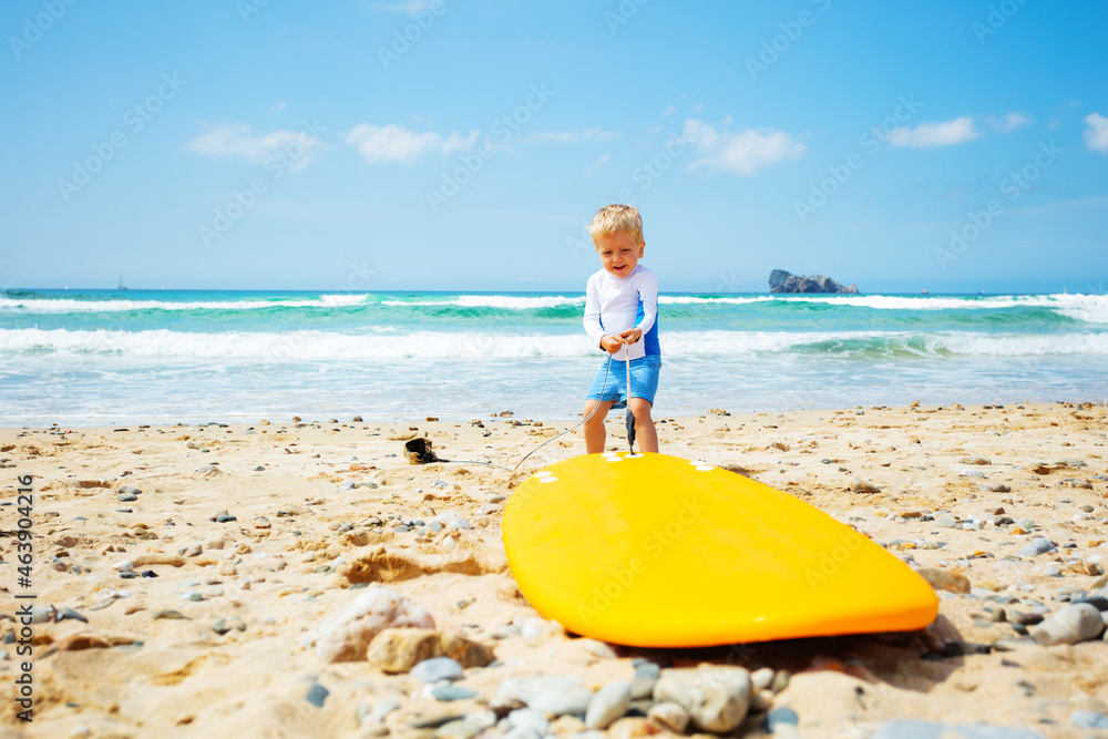 幼童站着把冲浪板拉向海浪