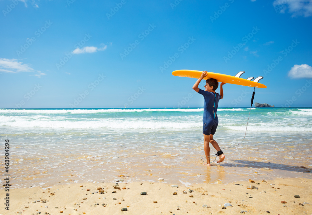 View from behind of a boy enter sea with surfboard