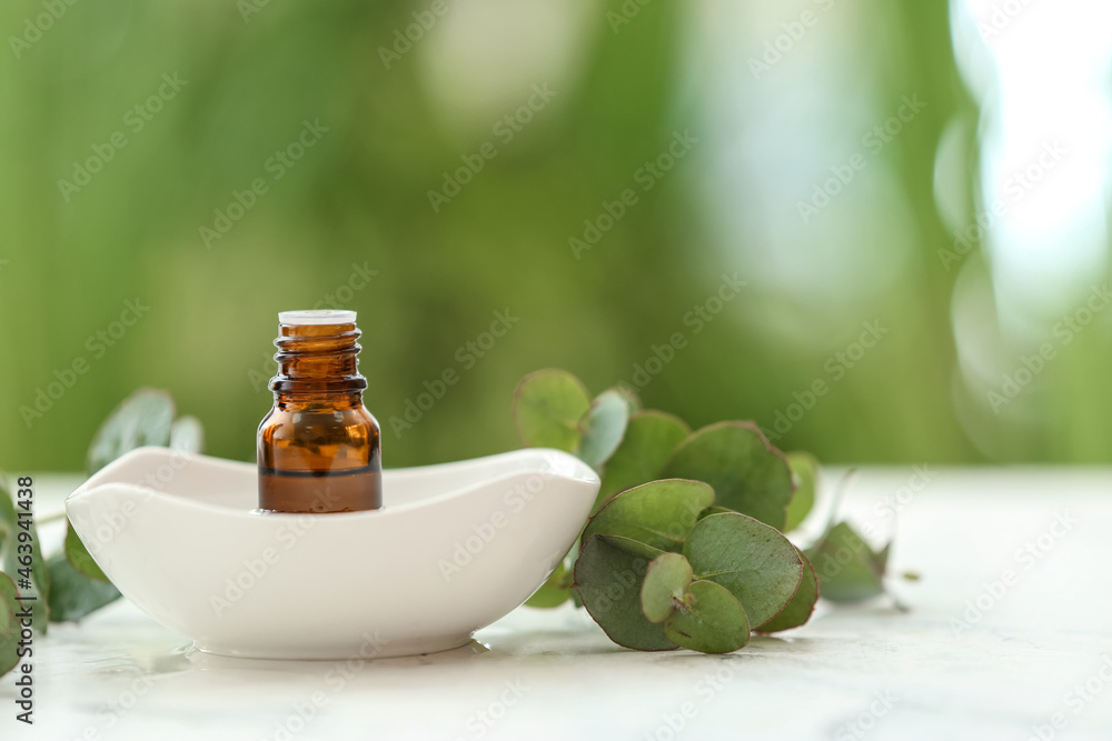 Bottle of essential oil and bowl on table